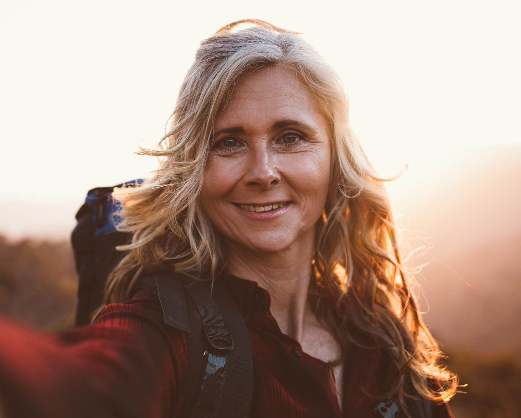 smiling woman taking a selfie with her camera in the mountains