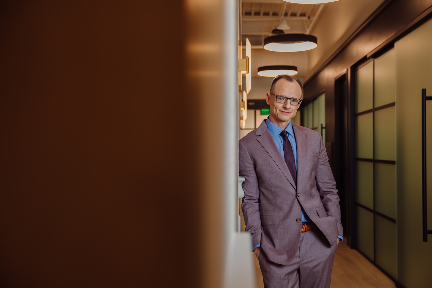 Dr. Wojciech Przylecki in suit leaning on wall